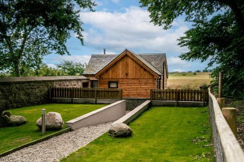 a house with a fence and a yard with rocks at The Auld Reekie in Barbaraville