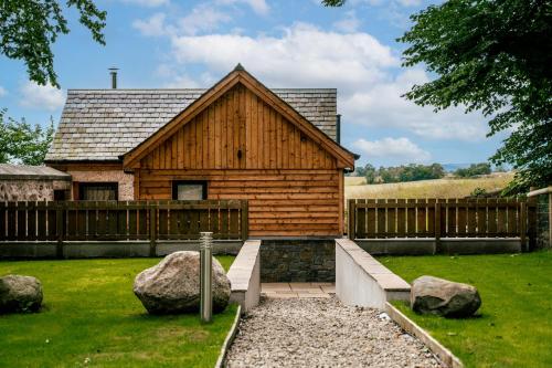 a wooden house with a fence and some rocks at The Auld Reekie in Barbaraville