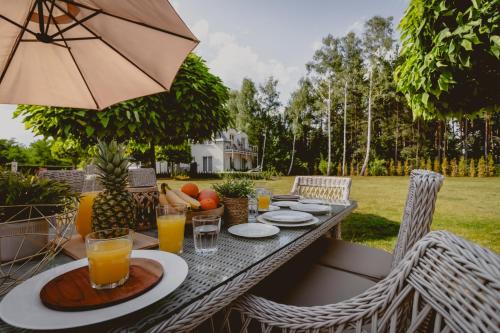 a table with an umbrella and some drinks on it at Golden Glamping nad Narwią in Lubiel Stary