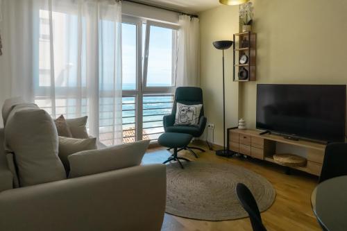 uma sala de estar com um sofá, uma televisão e uma cadeira em ALMA DE MALPICA apartamento nuevo en el centro em Malpica de Bergantiños