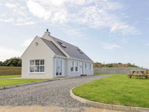 a white house with a pitched roof on a gravel driveway at The Haven in Falcarragh