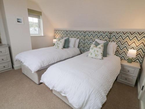 two beds in a bedroom with white sheets and pillows at The Haven in Falcarragh