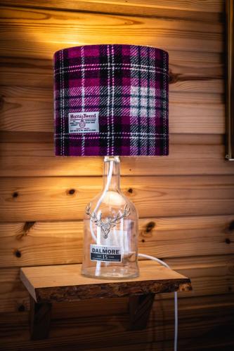 a bottle sitting on a table with a lamp at Delny Glamping and Farm Animals in Invergordon