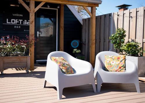 zwei weiße Stühle mit Kissen auf einer Terrasse in der Unterkunft Loft 32 in Winsum