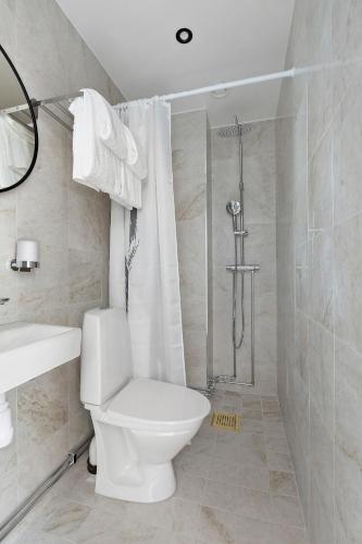 a white bathroom with a toilet and a shower at At Old Town Aparthotel in Stockholm