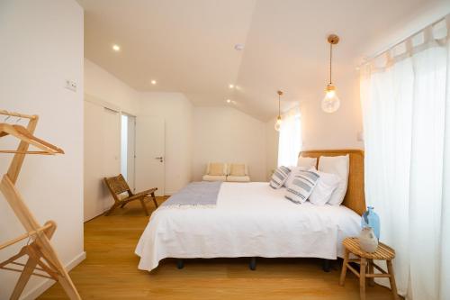 una camera da letto con un grande letto bianco con cuscini di Lookout Nazaré a Nazaré