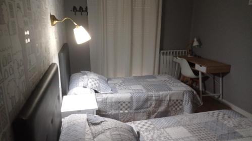 1 Schlafzimmer mit 2 Betten, einem Schreibtisch und einer Lampe in der Unterkunft Serendipia Apartamentos 3 in Logroño