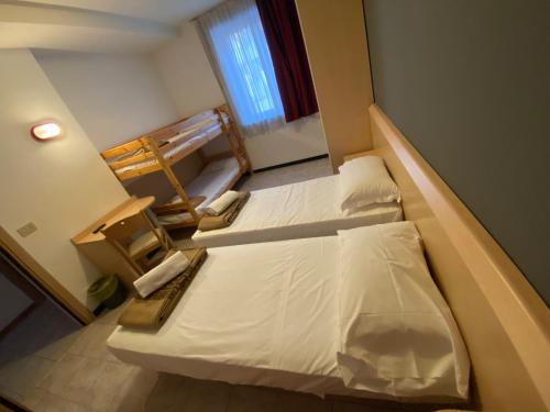 a small room with two beds and a window at Hotel Mazzini in Lido di Jesolo