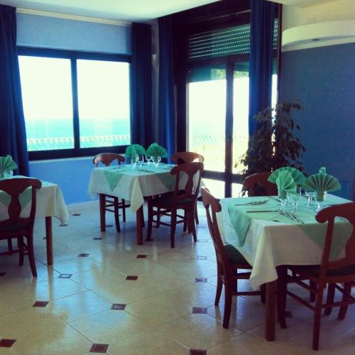 a dining room with tables and chairs and windows at Bellevue del Golfo Hotel & Spa in Sferracavallo