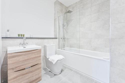 a bathroom with a tub and a toilet and a sink at Stylish 2 Bedroom Apartment Central Birmingham in Birmingham