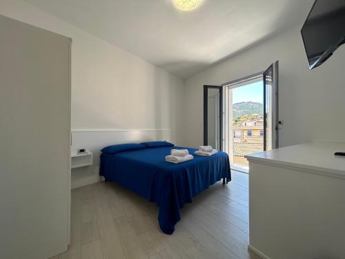 una camera con un letto blu e una grande finestra di Domu Dina Affittacamere 4 a Tertenìa