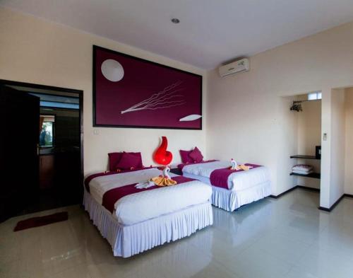 two beds in a room with a red vase on them at Melaya beach resort 3 in Penginuman