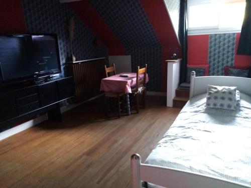 a room with a bed and a table and a tv at Havre de paix au bords de l'Eure - divers hébergements in Neuilly