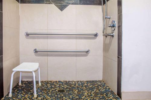 a shower with a white stool in a bathroom at Days Inn by Wyndham Humble/Houston Intercontinental Airport in Humble