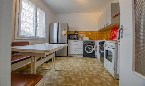 a kitchen with a table and a refrigerator at Le gite des deux familles in Chauffour-lès-Bailly