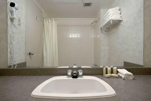 a bathroom with a sink and a large mirror at Howard Johnson by Wyndham Portage La Prairie in Portage La Prairie