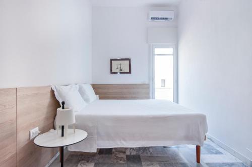 a white bedroom with a white bed and a table at THE VIEW B&B, terrace & more in San Foca