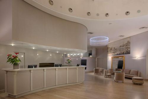 a lobby with a waiting area with chairs and a counter at NH Genova Centro in Genoa