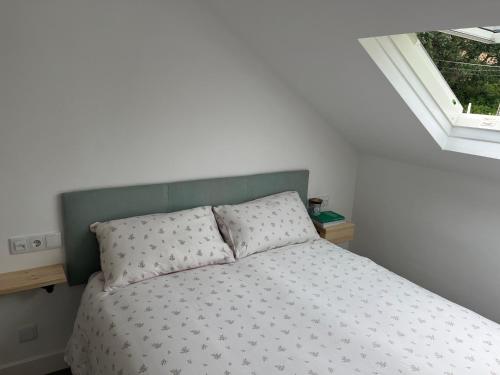 Ático con vistas en Raxó في راكسو: غرفة نوم مع سرير مع اللوح الأمامي الأخضر ونافذة