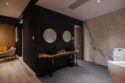 baño con paredes negras y mesa con 3 espejos en Park Plazza, en Korçë