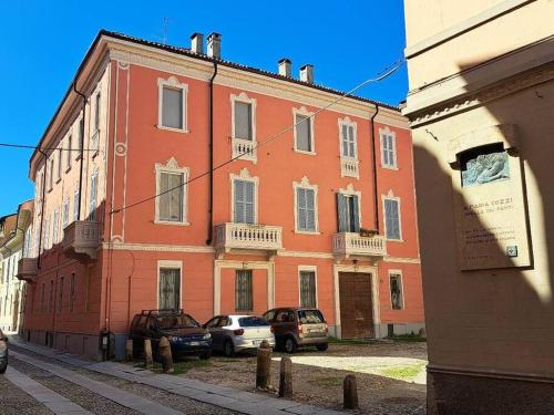 a large orange building with cars parked in front of it at Dimora Boezio7, cozy and charming place in center with private parking in Pavia