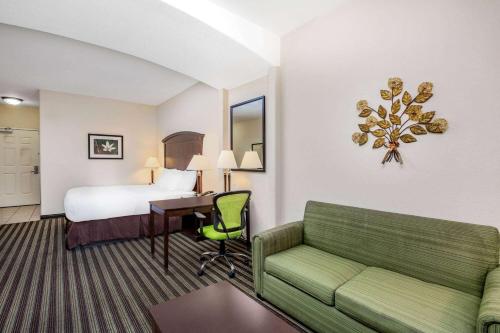 Habitación de hotel con cama y sofá verde en La Quinta by Wyndham Fowler, en Fowler