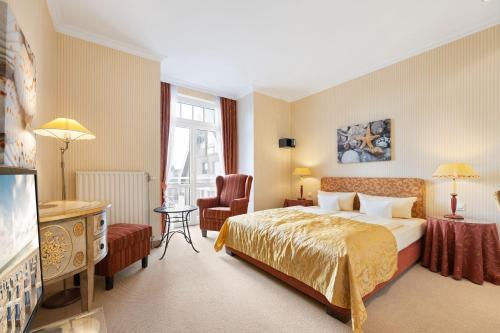 um quarto de hotel com uma cama e uma cadeira em Strandhotel Sylt GmbH em Westerland