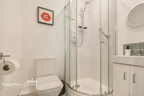 a bathroom with a shower and a toilet and a sink at Woodleigh in Cawsand