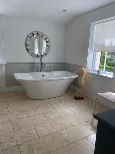 uma banheira branca na casa de banho com um espelho em Giffnock Rooms em Giffnock