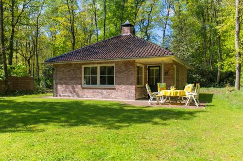 a small house with a table and chairs in a yard at Bungalowpark Bij de Bronnen in Nutter