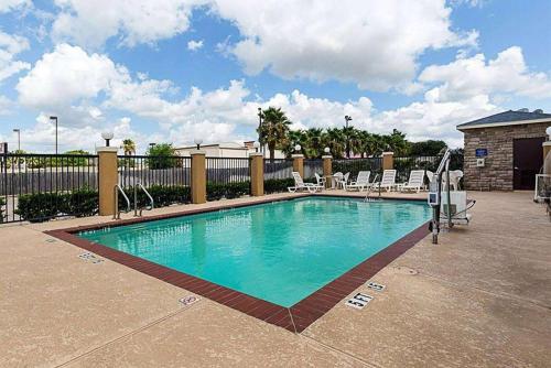 a large swimming pool with chairs and a fence at Days Inn & Suites by Wyndham Houston / West Energy Corridor in Houston