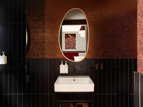 a bathroom with a white sink and a mirror at Hotel Morris Sydney, Handwritten Collection in Sydney