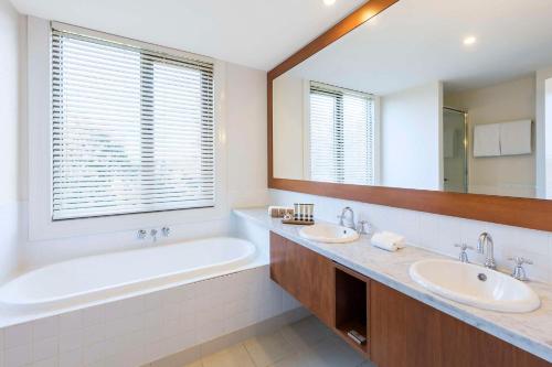 een badkamer met 2 wastafels, een bad en een grote spiegel bij Yarra Valley Lodge in Wonga Park