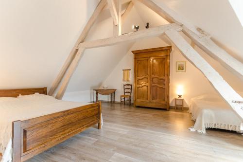 um quarto no sótão com uma cama e uma porta de madeira em Le gite de l'orvin em Courgenay