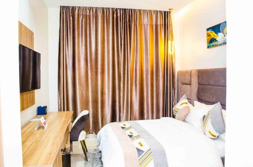 um quarto de hotel com uma cama, uma secretária e cortinas em Ozinny Signatures Hotel em Jidu