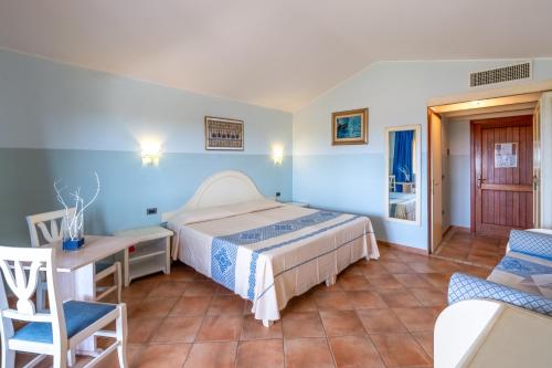 a bedroom with a bed and a table and a chair at Hotel Luci Del Faro in Calasetta