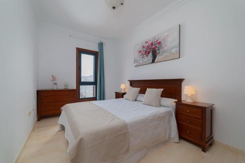 a white bedroom with a large bed and a mirror at Mireya Apartment in Playa Blanca