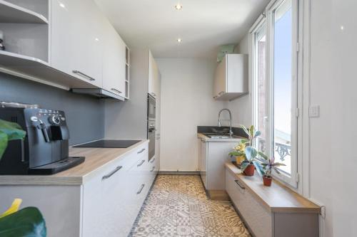 une cuisine avec des placards blancs et une grande fenêtre dans l'établissement Appartement Heinrich - Welkeys, à Boulogne-Billancourt