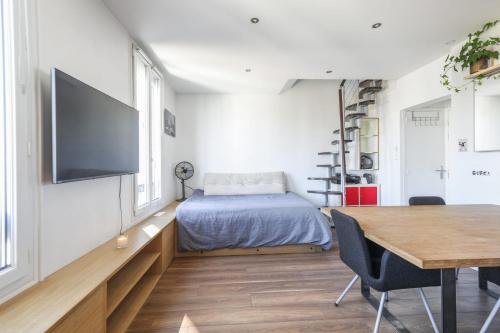 une chambre avec un lit, une table et une télévision dans l'établissement Appartement Heinrich - Welkeys, à Boulogne-Billancourt