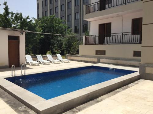 a swimming pool with chairs and a building at Primer Hotel in Yerevan