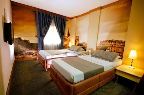 a hotel room with two beds and a television at Eurotel Makati in Manila