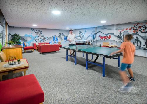a boy playing ping pong in a room with a ping pong table at JUFA Hotel Altenmarkt-Zauchensee in Altenmarkt im Pongau