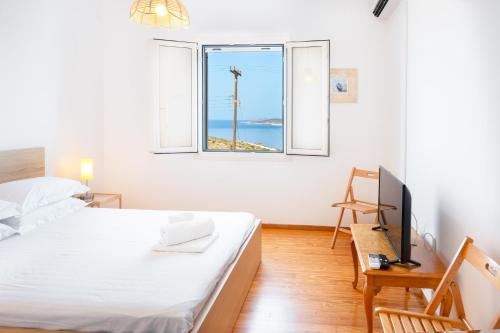 a bedroom with a bed and a desk and a window at Gaia Seaview Residence Irakleia in Áyios Yeóryios
