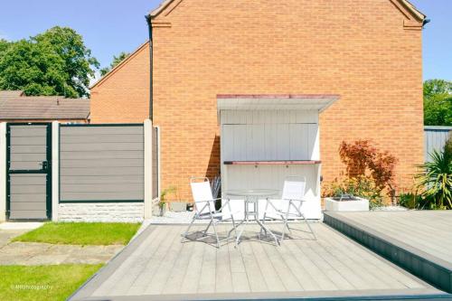 eine Terrasse mit 2 Stühlen und einem Tisch vor einem Gebäude in der Unterkunft Modern 3 bed home, Chesterfield in Chesterfield