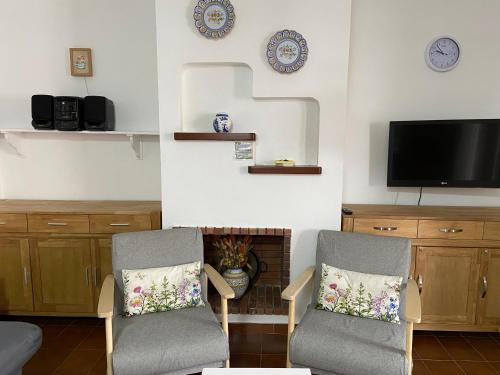 a living room with two chairs and a flat screen tv at Siestamar in Cala en Porter