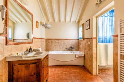 a bathroom with a tub and a sink and a mirror at Hotel San Michele in Cortona
