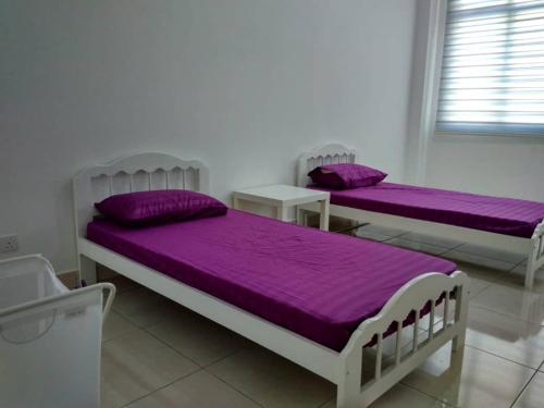 2 camas en una habitación con sábanas moradas en HOMESTAY BATU PAHATKU- HOMESTAY IMAN en Batu Pahat
