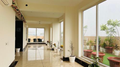 an empty hallway with potted plants and large windows at Amahi Inn I Signature Towers in Gurgaon