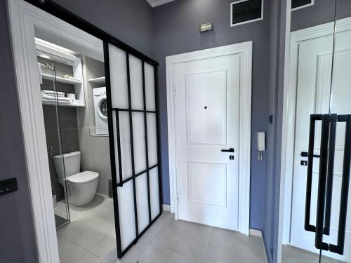 La salle de bains est pourvue d'une porte blanche et de toilettes. dans l'établissement Step apartment, à Belgrade