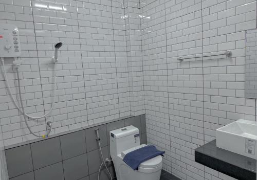 La salle de bains est pourvue de carrelage blanc, de toilettes et d'une serviette bleue. dans l'établissement โรงแรมดีดีธาราอิน - DD tara inn, à Uttaradit